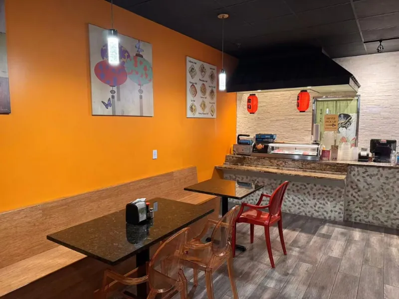 Modern dining area with orange walls and cozy seating at Wok & Roll Express, an Asian Restaurant in Leawood